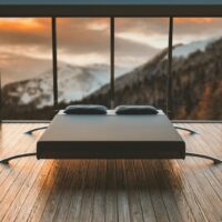 black mattress in front of a large window behind a mountain