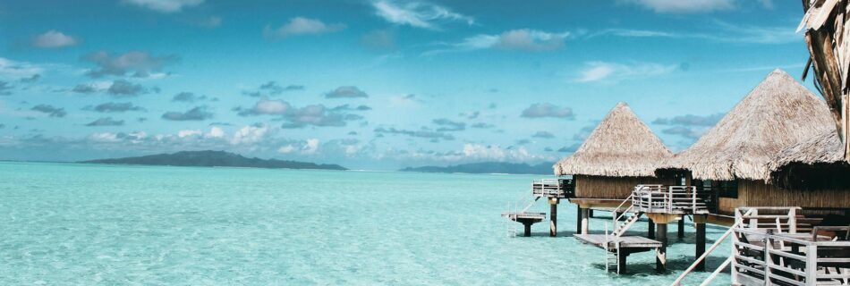 three brown wooden cottage and sea