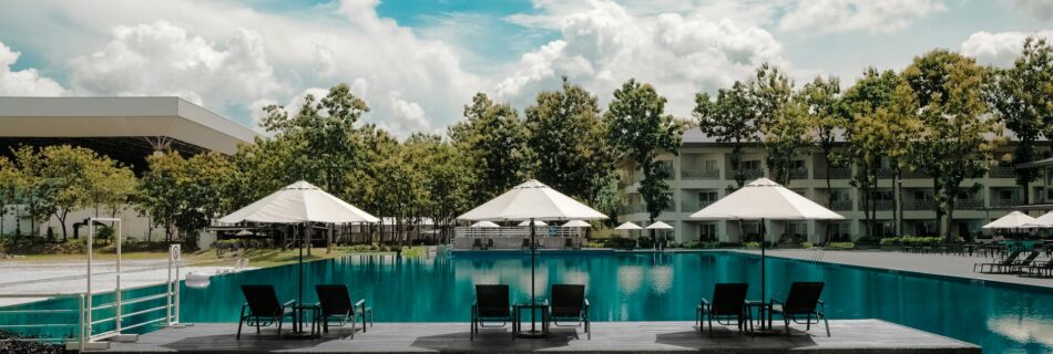 black outdoor lounge chair in between blue swimming pool under white cloudy blue sky