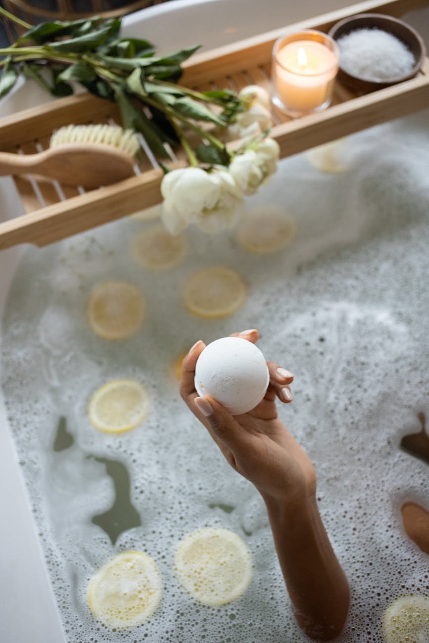 crop woman with bath bomb sitting in tub
