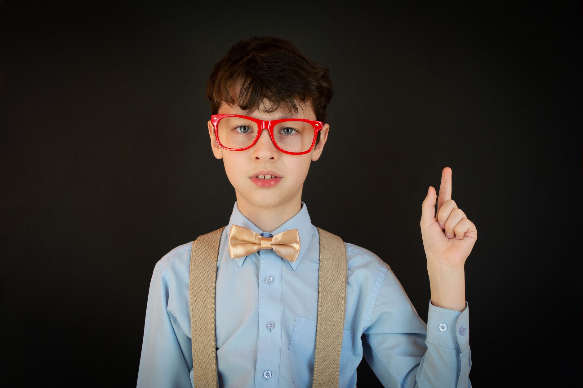 little boy with glasses pointing finger up
